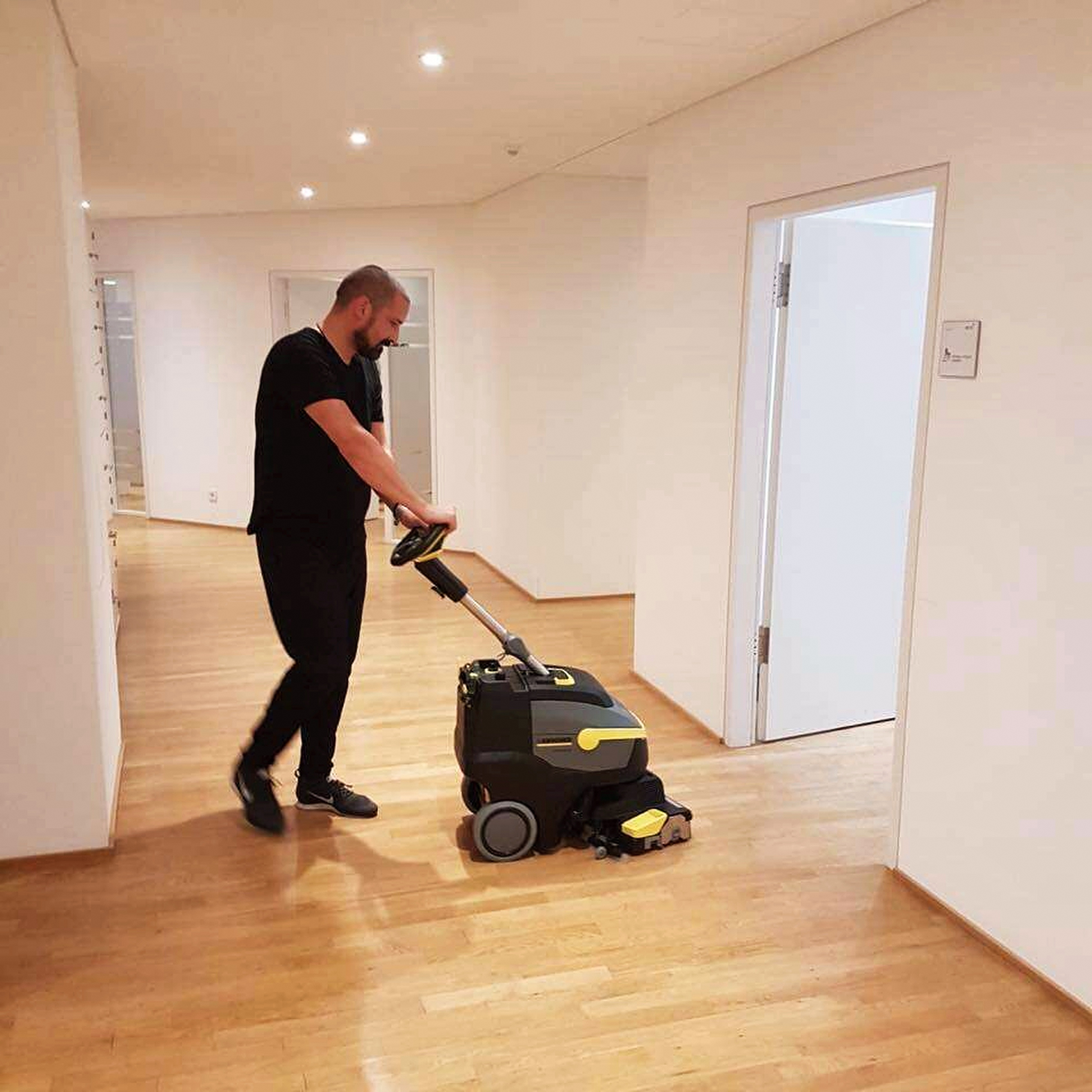 Mitarbeiter mit Bodenreinigungsmaschine in einem hellen Innenraum